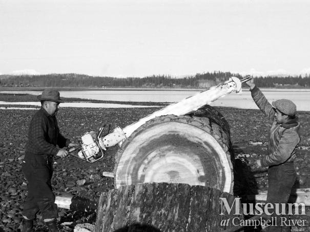 Men on beach with large log