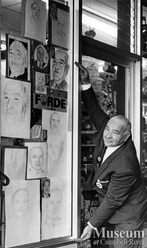 Ken Forde poses with many portraits of himself